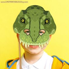 a young boy wearing a green dinosaur mask