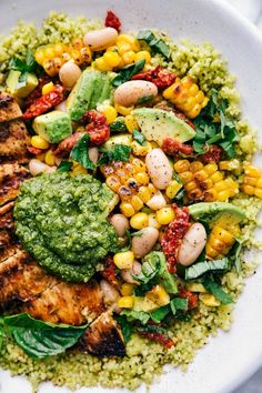 a white bowl filled with meat and veggies on top of couscous