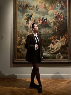 a woman standing in front of a painting