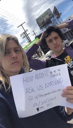 two people holding up a sign that says ask us anything