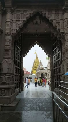 people are walking under an ornate archway