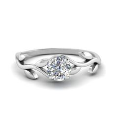 a white gold engagement ring with a round diamond in the center and an intricate design on the band