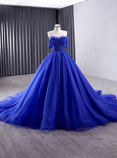 Ominously beautiful, this royal blue prom dress is designed to make a grand statement. The off-the-shoulder neckline is adorned with delicate ruffles, creating a romantic and whimsical look that is perfect for any formal occasion. The structured bodice features intricate boning, ensuring a flattering fit that accentuates the waist and creates an elegant silhouette. The voluminous skirt, made of layers of soft tulle, flows gracefully to the floor, providing a sense of drama and movement. Subtle glitter accents throughout the fabric catch the light, giving the gown a magical, sparkling effect. This dress is a perfect blend of classic elegance and modern design, making it a standout choice for any prom or gala. With its luxurious fabric and impeccable craftsmanship, this gown is designed to m Off The Shoulder Prom Dress, Colored Wedding Gowns, Full Tulle Skirt, Wedding Dress Cap Sleeves, Wedding Dress Champagne, Senior Prom Dresses, Royal Blue Prom Dresses, Blue Tulle, Wedding Dresses Beaded