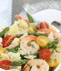 pasta salad with shrimp, asparagus, tomatoes and green beans in a white bowl