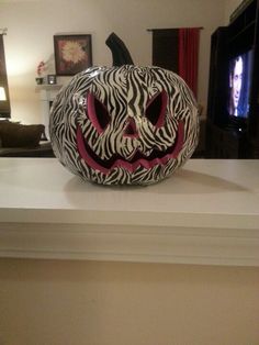 a zebra print pumpkin sitting on top of a mantle