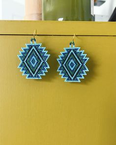 a pair of blue beaded earrings hanging from a hook on a yellow cabinet door