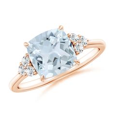 a ring with an aqua blue topazte and three diamonds on the side, in rose gold