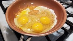 three eggs in a frying pan sitting on top of a gas stove burner