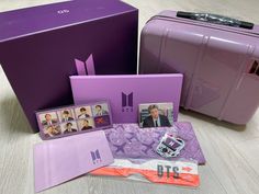 the purple suitcase has pictures on it and is next to two other pieces of luggage