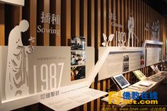 an exhibit area with wooden paneled walls and various displays on the wall, including photographs