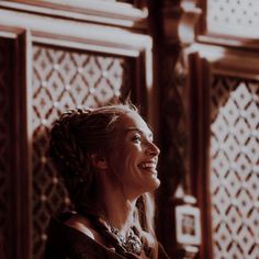 a woman with braids smiling and looking up at something in the distance behind her