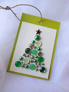 a christmas tree made out of buttons is hanging on a white card with green string