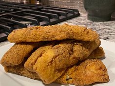 some fried food on a white plate next to a black stove top and countertop