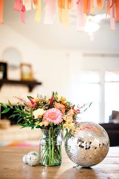 a vase filled with flowers sitting on top of a table next to a disco ball