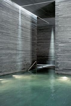 an indoor swimming pool with water running down the wall and steps leading up to it