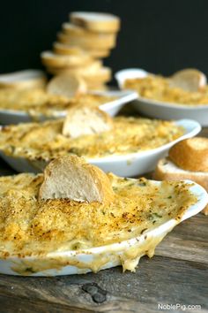 several bowls filled with food sitting on top of a wooden table next to bread slices