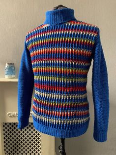 a blue sweater with multicolored stripes is on a mannequin head stand