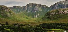 the mountains are covered in green grass and trees