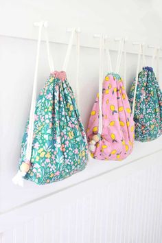 three drawsacks hanging on the wall with flowers and fruit print fabric in them