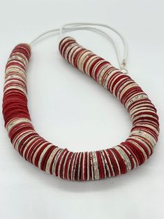 a red and white necklace with silver beads