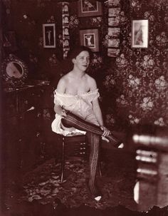 an old black and white photo of a woman sitting on a chair in a room