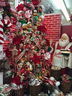 a christmas tree is decorated with candy canes and other holiday decorations in front of a red brick wall