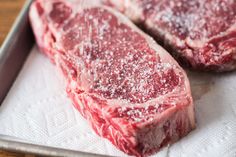 two pieces of raw meat sitting on top of a cutting board