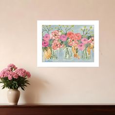 a vase with pink flowers sitting on top of a wooden table next to a wall