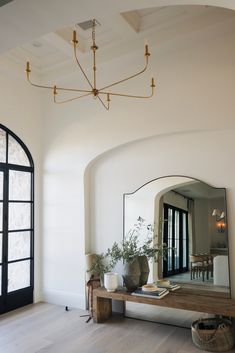 a large mirror sitting on top of a wooden table next to a wall mounted light