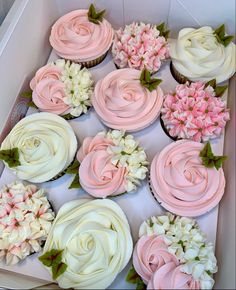 a box filled with cupcakes covered in pink and white frosting flowers on top of each one