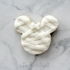 a mickey mouse cookie with white icing on a marble surface