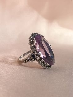 Vintage silver Victorian gothic ring from Ireland featuring an enchanting oval cut amethyst nestled in a rhinestone halo setting. Great vintage condition, one rhinestone missing Size: 5.75 resizable* Weight: 6.3 grams Band: 28.3 mm (front), 1.4 mm (back) Amethyst: 20.0 mm x 11.5 mm oval cut Hallmarks: 'Stfuling' for maker's mark Gothic Ring, Gothic Rings, Halo Setting, Victorian Gothic, Maker's Mark, Makers Mark, Oval Cut, Vintage Silver, Halo