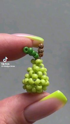 a hand holding a tiny green beaded tree