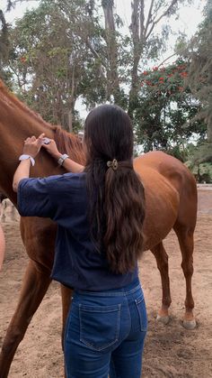 a woman standing next to a brown horse