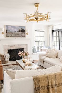 a living room filled with furniture and a fire place under a chandelier in front of a window