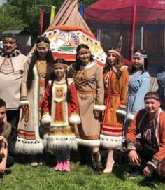 a group of people standing next to each other in front of a teepee tent