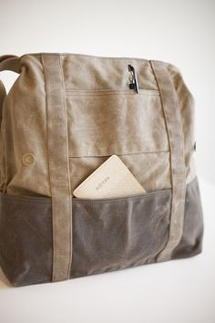 a brown bag with two pockets and a book in the bottom pocket, sitting on a white surface