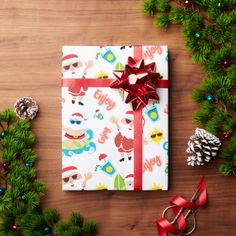 a christmas present wrapped in wrapping paper with birds and pine cones on the table next to it