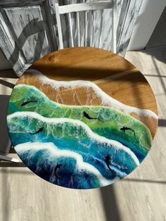 a wooden table topped with a painting of birds flying over the ocean on top of waves