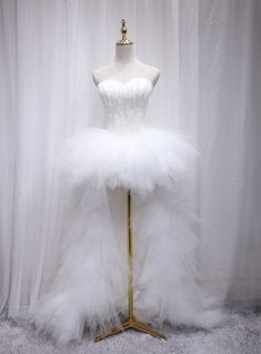 a mannequin dressed in white tulle and gold trimmings on a stand