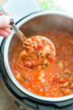 a ladle full of chili and beans is being held up