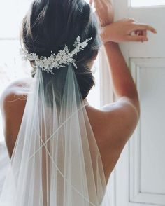 the back of a bride's head wearing a veil with flowers and pearls on it