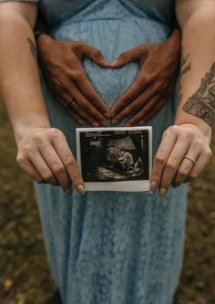 a pregnant woman holding her belly in the shape of a heart with hands on it