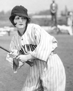 an old black and white photo of a baseball player holding a bat on the field