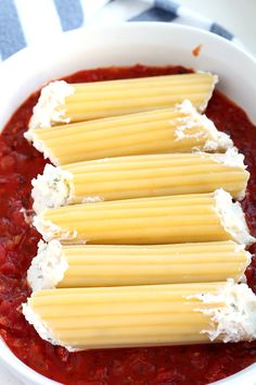 four pieces of cheese on top of some pasta in a white bowl with red sauce