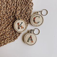 two cross stitch keychains sitting next to each other