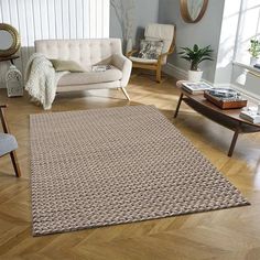 a living room filled with furniture and a rug on top of a hard wood floor