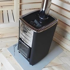 a black stove sitting on top of a wooden floor next to a white wall with wood slats