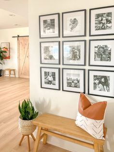 a wooden bench sitting next to a wall with pictures on it