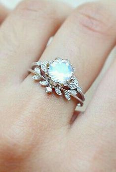 a close up of a person's hand wearing a ring with an oval stone